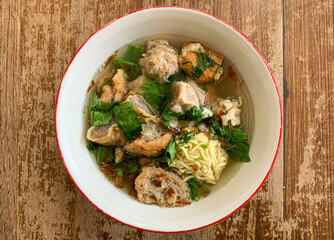A bowl of meat ball soup with fresh vegetables on the old wooden table