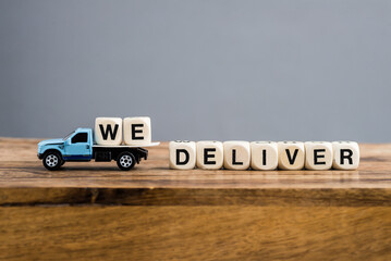 WE DELIVER.  composition of a toy truck and cubes with the words on a gray background. Logistics and wholesale.