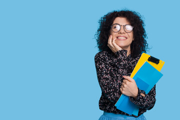Caucasian student in casual clothes holding books isolated over blue background studio portrait...