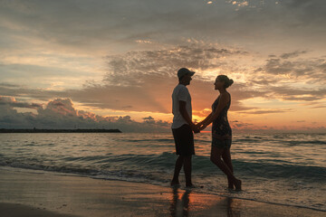 Silueta de una  pareja de enamorados tomados de las manos al amanecer