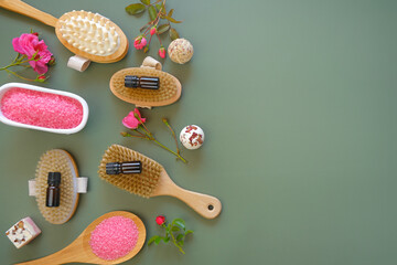 Rose oil and cosmetics salt with rose extract and body brushes on a green background.Aromatherapy...