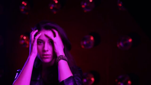 Female model in glowing light moving like striking a pose. Happy girl having fun in club. Caucasian sexy young pretty woman look at the camera. Close up. Slow motion. Pink and blue neon light.