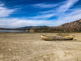 Foto op Canvas Drought lake and old fishing boat. Old boat on the drought lake. Drought concept. Drought crisis because of global warming. Global warming causes climate change. Drought lake due to global warming. © Mete Caner Arican