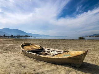 Foto auf Alu-Dibond Drought lake and old fishing boat. Old boat on the drought lake. Drought concept. Drought crisis because of global warming. Global warming causes climate change. Drought lake due to global warming. © Mete Caner Arican