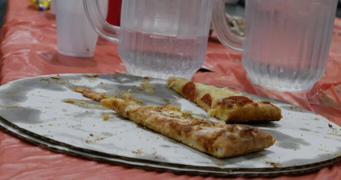 Sad looking leftover birthday party event pizza pepperoni and cheese on table with pitchers of water - in Cinema 4k (30fps slowed from 60fps).