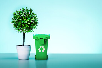 Garbage can and green tree in pot on mint color background with copy space. Recycling garbage separation. Eco concept.