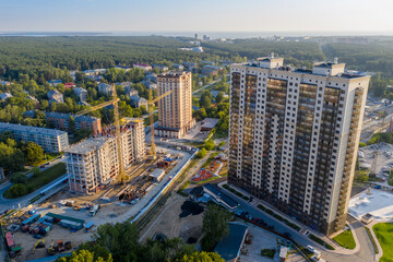 Aerial view of high-rise buildings under construction on the edge of the forest