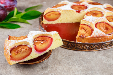 Piece of tasty plum pie covered with powdered sugar.