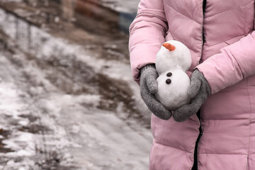 Snowman is melting in women's hands..Thaw warm winter or early spring. climate change as a result of global warming 