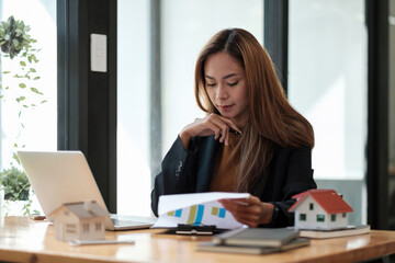 Asian business woman working for interest, taxes and profits to invest in real estate and home buying