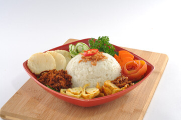 Nasi uduk Betawi plating in a red plate, coconut rice complete with side dishes on a wood table 