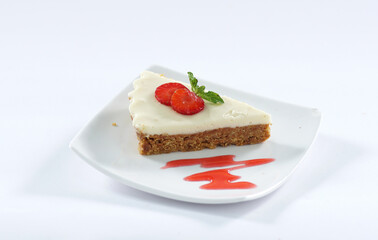 A white plate of delicious no bake cake with cream and strawberry sauce