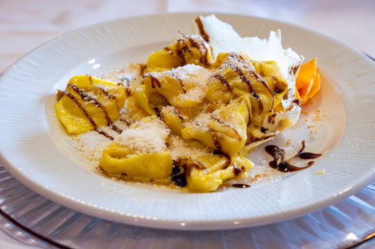 Italian food, fresh home made pumpkin stuffed pasta tortellini or ravioli dumplings with parmesan parmigiano reggiano cheese and Balsamico Vinegar of Modena, Parma, Emilia Romagna, Italy