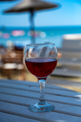 Drinking of cold rose wine in lounge bar on sunny sandy beach with blue sea water on background