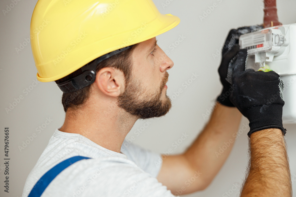 Wall mural Closeup shot of serious heating fitter checking gas consumption at gas pipe and meter counter