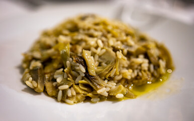 Italian cuisine, fresh vegetarian risotto made with young artichoke heads close up.