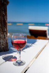 Drinking of cold rose wine in lounge bar on sunny sandy beach with blue sea water on background