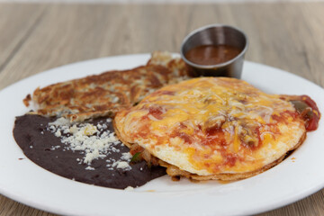 Huevos rancheros with eggs, refried beans, hashbrowns for a delicious Mexican breakfast meal to start the day