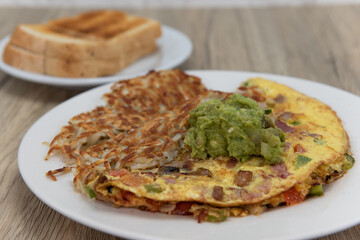 Eggs scrambled in a hearty omelette served with hash browns and toast for a tradional breakfast
