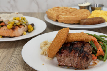 Juicy grilled steak and onion rings stand out on the buffet table full of meals to eat