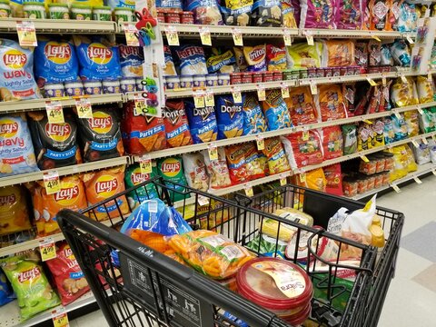 Wilmington, Delaware, U.S.A - January 8, 2022 - A shopping cart filled with groceries on the snacks aisle inside a supermarket