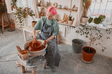 Young potter working on pottery wheel in workroom