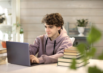 young man, student studying at home, looking at a laptop