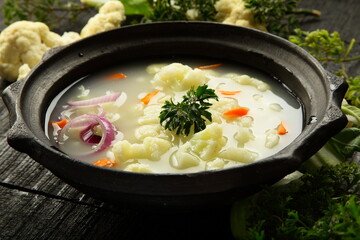 Homemade delicious cauliflower vegetable soup cooked in earthenware., traditional recipes background.