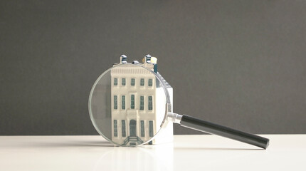 Mini property with magnifying glass. Search for property concept.