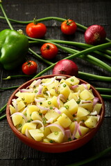 Delicious organic fresh potato salad with herbs and vegetables.