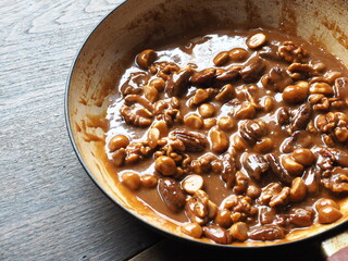 caramel toffee sauce with pecan, walnut and macadamia nuts in pan