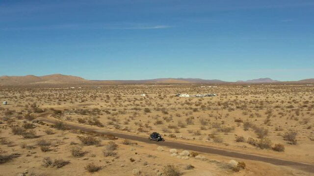 An off-highway vehicle driving along dirt trails in the Mojave Desert landscape - aerial view