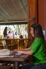 Latin woman wearing green blouse, sitting in a coffee shop working on her laptop