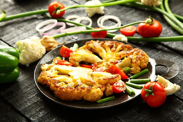 Iron skillet cooking- delicious roasted cauliflower ears  and fresh vegetables,  traditional recipes background, 