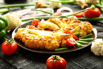 Iron skillet cooking- delicious roasted cauliflower ears  and fresh vegetables,  traditional recipes background, 