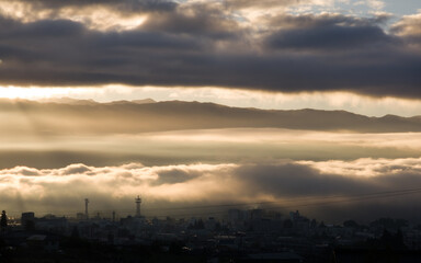 Iida, Nagano, Japan, 2021-11-10 , Clouds lighted by the sun during sunrise in early morning over Iida city, in Nagano, Japan.