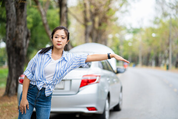 Asian young woman hitchhiking on highway, needing emergency assistance, having road accident