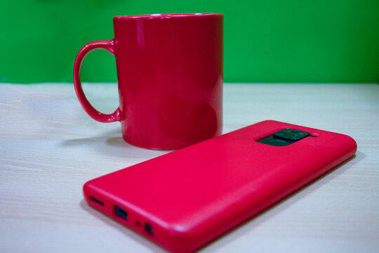 mug rojo en oficina con celular y aud&iacute;fonos