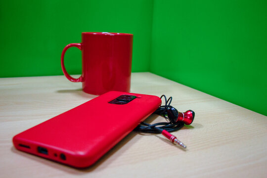 mug rojo en oficina con celular y aud&iacute;fonos