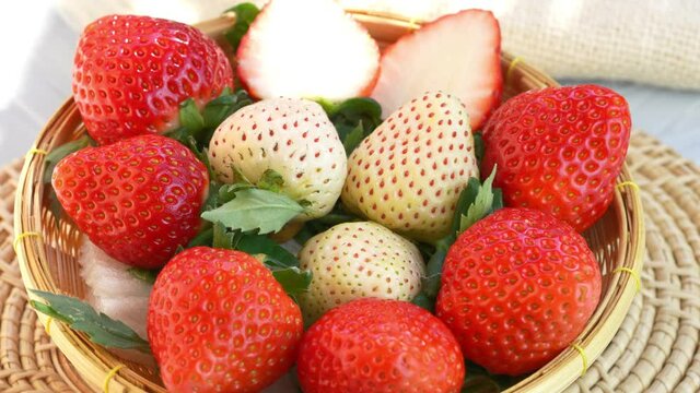 Fresh red and white strawberries in a wooden basket on wooden background, Red Strawberries and Pine berry or Hula strawberry in Bamboo basket