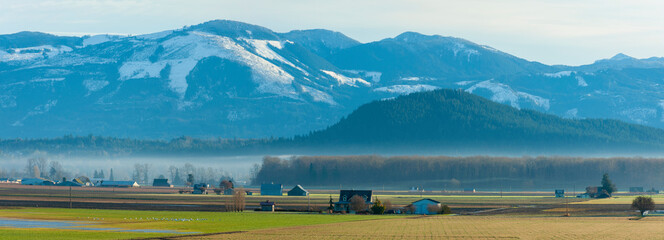 Skagit Valley Farmland With the North Cascade Mountains in the Background. A thin ground fog layer separates the Cascades from the agricultural gem of the Pacific Northwest-the Skagit Valley, WA. © LoweStock