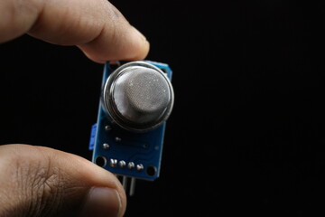 MQ2 gas sensor module held in hand isolated on black background