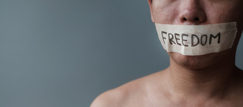 Man with mouth sealed in adhesive tape with Freedom message. Free of speech, freedom of press, Human rights, Protest dictatorship, democracy, liberty, equality and fraternity concepts