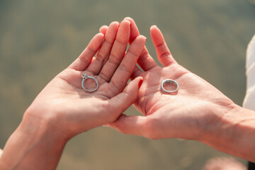 Two silver wedding rings are placed on the hands of men and women.