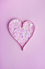 Valentines day composition. Sparkle confetti shape of heart on pastel purple background. Top view, flat lay, vertical, minimal