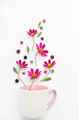 Composition of berries and flowers over a cup.