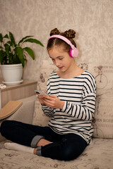 Fototapeta premium A cute teenage girl sits on the couch and chats online. Communication. Home.