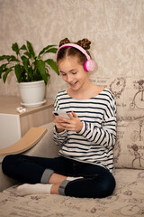 Fototapeta premium A cute teenage girl sits on the couch and chats online. Communication. Home.