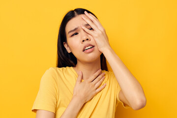 Portrait Asian beautiful young woman in a yellow t-shirt holding his head discontent studio model unaltered