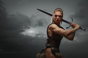 Fantasy woman warrior in laether armor stained with blood and mud, holding sword. Cosplayer historical viking - 479698863
